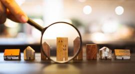Photo d'une loupe qui zoome sur des maquettes de maisons illustrant l investissement en lmp