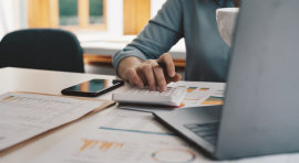 Personne devant une calculatrice, un ordinateur et des graphiques pour apport investissement locatif
