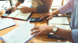 Photo de personnes sur une table de réunion avec calculatrice et graphiques pour des demarches activites LMNP