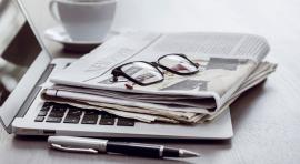 Ordinateur pose sur bureau avec un journal et des lunettes de vue dessus illustrant les actualites d epargne