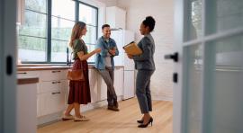 Trois-personnes-debout-en-train-de-discuter-de-gestion-locative-dans-une-agence-immo