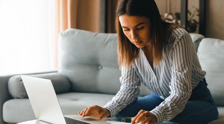 Femme en train de faire des calculs devant son ordinateur