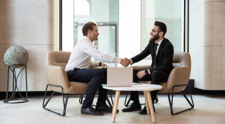 2 hommes se serrant la main devant un ordinateur