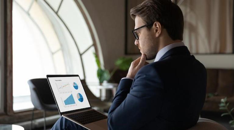 Homme assis devant un ordinateur se posant 5 questions avant d investir en crowdfunding immobilier