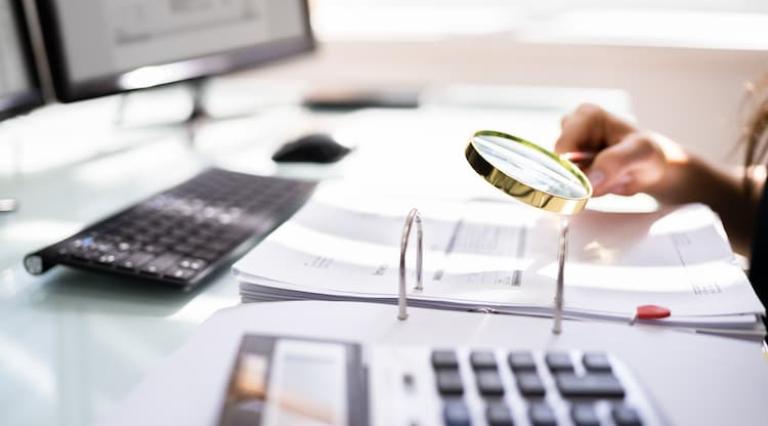 Personne tenant une loupe au-dessus d'un document de SCPI