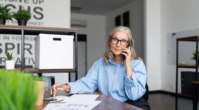 Femme au telephone devant des documents d'epargne