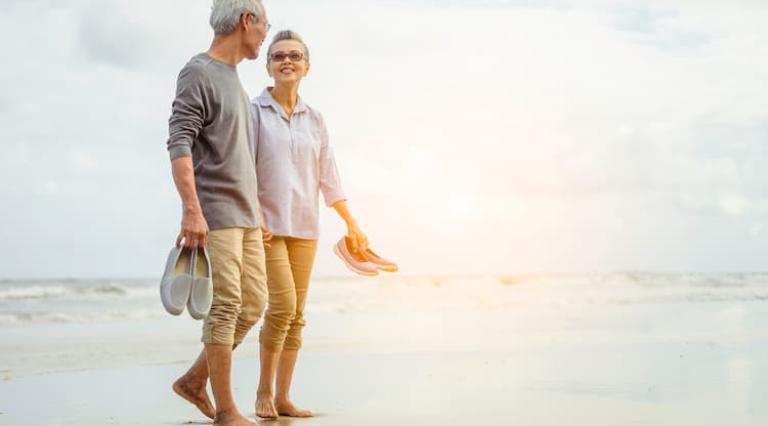 Photo d'un couple senior homme/femme sur la plage ayant investi dans un PER