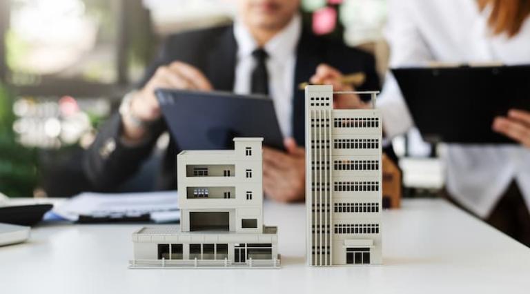 Photo de 2 personnes devant des maquettes d'immeubles pour acheter en vefa