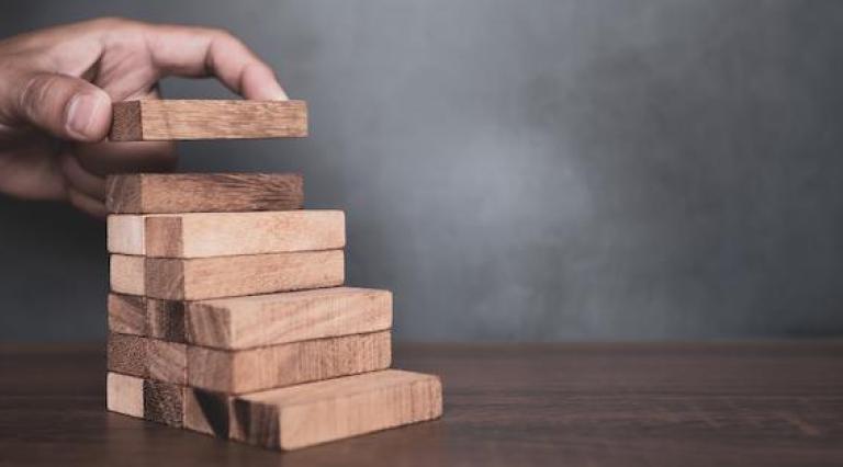 Main qui empile des morceaux de bois symbolisant les meilleurs placements sans risques