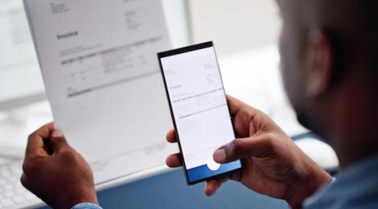 Photo d'un homme en train de faire une photo d'un document avec son smartphone illustrant l impact de la digitalisation sur le locatif