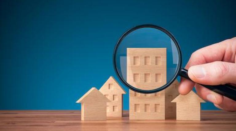 Photo d'une maquette de maison avec une loupe posée devant pour illustrer l investissement en lmnp