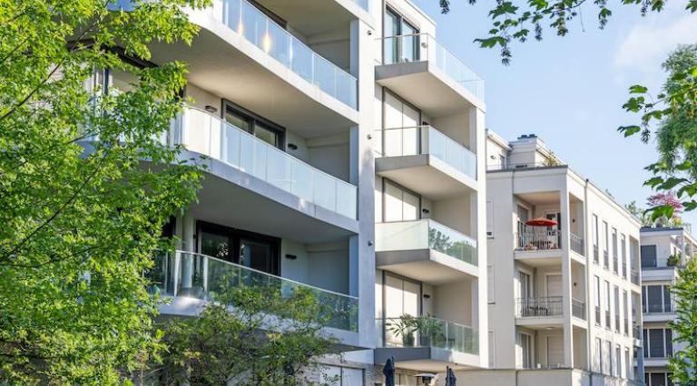 Photo d'un immeuble récent entoure d arbres illustrant la gestion d immeuble en investissement immobilier