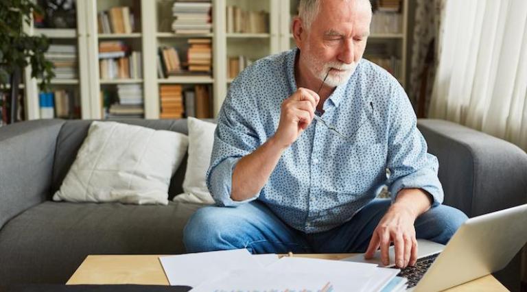 Senior-devant-un-ordinateur-et-des-documents-pièges-à-éviter-réussir-retraite-2024