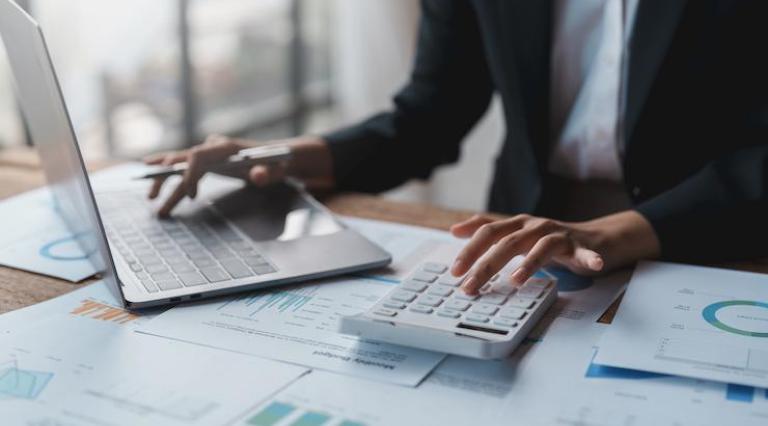 Mains d'une personne utilisant ordinateur et calculatrice SCPI vs PER
