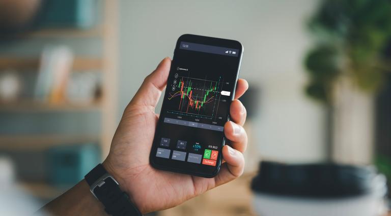 main-tenant-telephone-portable-regardant-graphiques-pour-tout-savoir-sur-la-cryptomonnaie