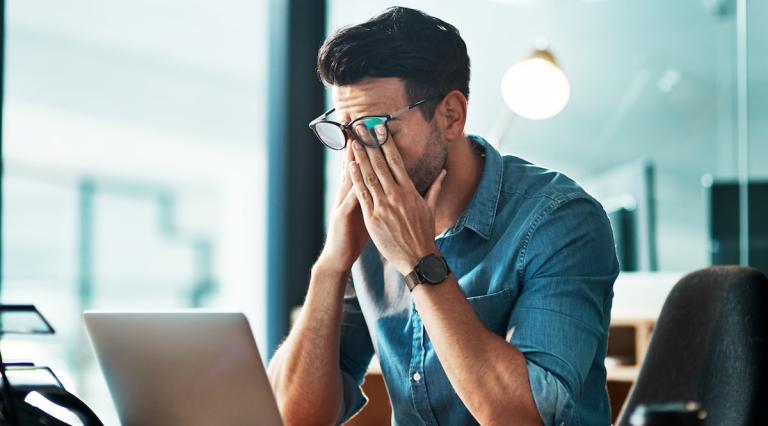 homme-se-tenant-la-tete-devant-ordinateur-illustrant-les-risques-de-la-cryptomonnaie
