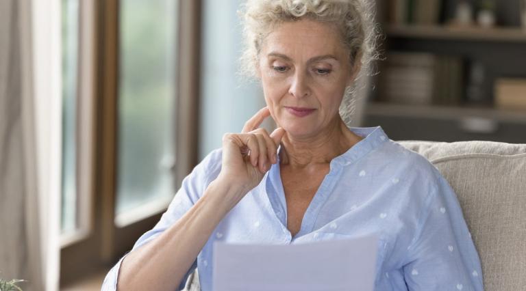 femme-agee-lisant-documents-en-reflechissant-a-retraite-par-capitalisation-vs-par répartition-quel-choix
