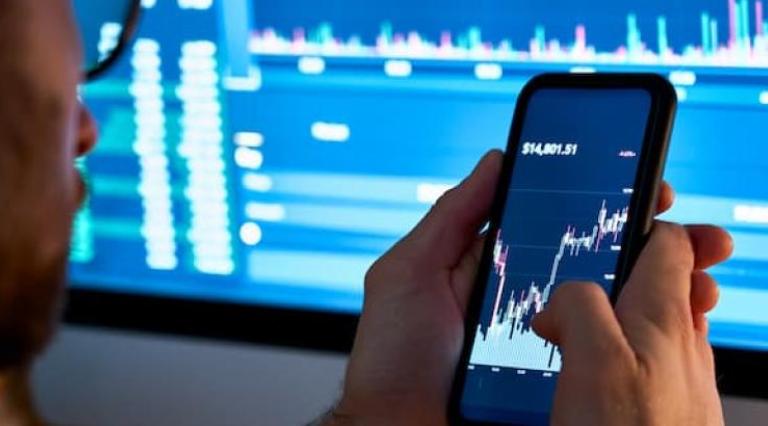 homme avec Smartphone affichant un graphique de bourse à l'écran pour investir 1000 euros