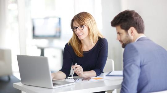 Une banquière et son client étudient avec un ordinateur portable la renégociation d'un crédit immobilier
